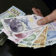 A money changer holds Turkish lira banknotes next to U