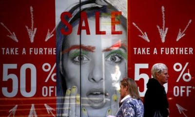 Pedestrians walk past a shop displaying advertising for a sale in central Sydney, Australia