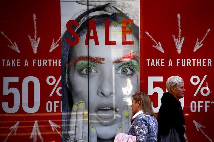 Pedestrians walk past a shop displaying advertising for a sale in central Sydney, Australia