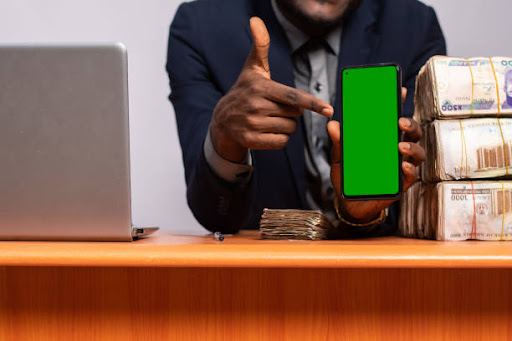 A black businessman showing his phone with a green screen display